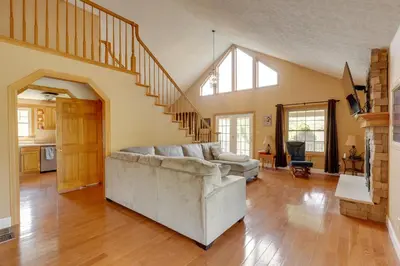 a living room with a couch and a staircase at Game Room and On-Site Pond Laurelville Retreat! in Laurelville