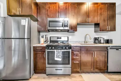 a kitchen with stainless steel appliances and wooden cabinets at Cle Suites 2BR 1BA 5 min Walk to Cle Clinic #8 in Cleveland