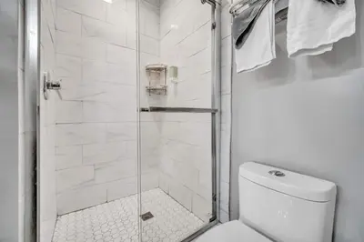 a white bathroom with a shower and a toilet at Cle Suites 2BR 1BA 5 min Walk to Cle Clinic #9 in Cleveland