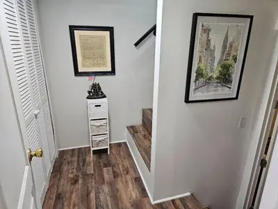 a hallway with a staircase with wooden floors and two pictures at College Park Bungalow in Winchester