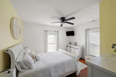 a white bedroom with a bed and a ceiling fan at College Park Getaway in Winchester