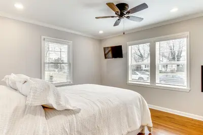 a white bedroom with a ceiling fan and windows at Screened Patio and Fire Pit Modern Westerville Home in Westerville