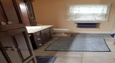 a bathroom with a toilet and a window and two rugs at Lambs Landing Huron Family Vacation Home in Huron