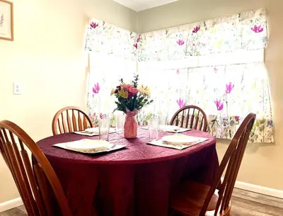 a dining room table with a vase of flowers on it at Emerald - GREAT PARK, 3br, Yard, Pet-Friendly in Paulding