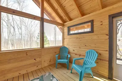 two blue chairs in a wooden room with windows at Hot Tub and Fire Pit Romantic Getaway in Frenchburg in Frenchburg