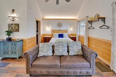 a living room with a couch in front of a bed at Hot Tub and Fire Pit Romantic Getaway in Frenchburg in Frenchburg