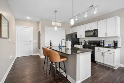 a kitchen with white cabinets and a counter with bar stools at City View Designer Elevator Covered Parking in Columbus