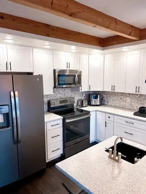 a kitchen with white cabinets and a stainless steel refrigerator at Cabin Sweet Cabin in Burlington