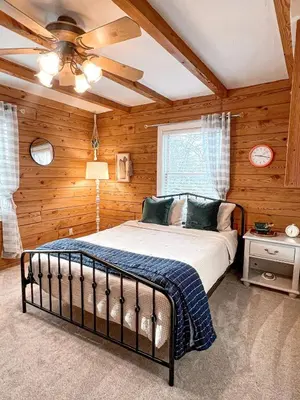 a bedroom with a bed in a room with wooden walls at Cabin Sweet Cabin in Burlington