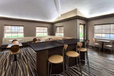 a bar with stools in a room with windows at Super 8 by Wyndham Copley Akron in Copley