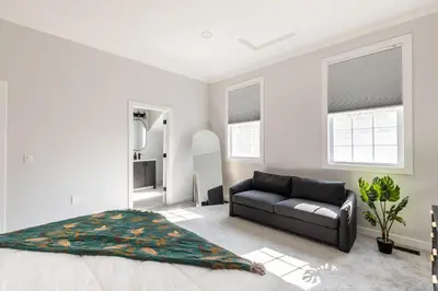 a bedroom with a bed and a couch and windows at Spacious & Cozy Central Cincinnati Home in Cincinnati