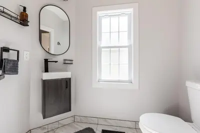 a white bathroom with a mirror and a sink at Spacious & Cozy Central Cincinnati Home in Cincinnati