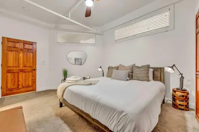 a white bedroom with a large bed and a wooden door at Lofts on 4th Penthouse, Sleeps 14, 2 units in Cleveland