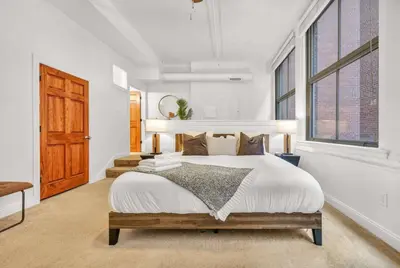 a white bedroom with a large bed and windows at Lofts on 4th Penthouse, Sleeps 14, 2 units in Cleveland