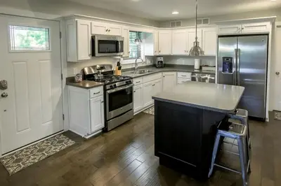 a kitchen with white cabinets and a stainless steel refrigerator at Sweet Private Cabin with Jacuzzi and Fire Pit in Ohio in Sugarcreek