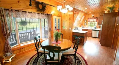 a dining room with a table and a kitchen at Romantic Forest Cabin with Amazing Private Deck and Spa in Ohio in Sugarcreek