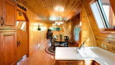 a large room with a table in a wooden house at Romantic Forest Cabin with Amazing Private Deck and Spa in Ohio in Sugarcreek