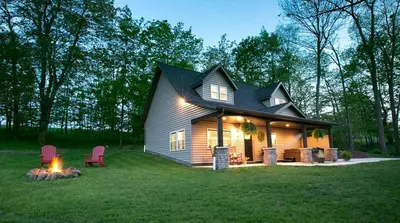 a small house with a fireplace in the yard at Beautiful Countryside Cabin with Hot-Tub and Pond Views in Ohio in Sugarcreek