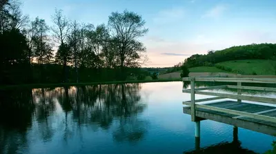 a lake with a dock in the middle of it at Beautiful Countryside Cabin with Hot-Tub and Pond Views in Ohio in Sugarcreek