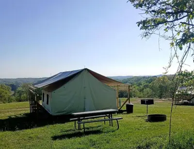 a large tent in a field with a picnic table at Impressive Tented Cabin with Peaceful Vistas and Fire Pit in Logan, Ohio in Logan