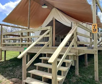 a wooden bed in a tent with a ladder at Breathtaking Family Friendly Tented Cabin in Logan, Ohio in Logan