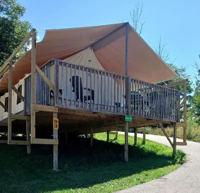a large tent with a deck in the grass at Sensational Tented Cabin Nestled Amidst Trees and Fire Pit Provided in Logan, Ohio in Logan