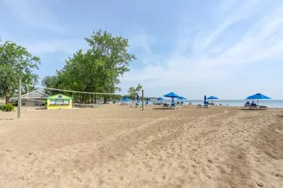a beach with chairs and umbrellas and the ocean at Furnished Screened Porch Baypoint Resort Home! in Marblehead