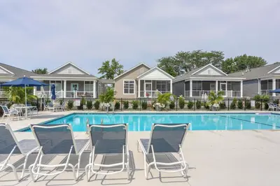 a pool with chairs and umbrellas in front of houses at Furnished Screened Porch Baypoint Resort Home! in Marblehead