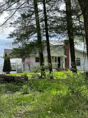 a white house with trees in front of it at Retreat on Lake Milton in Berlin Center