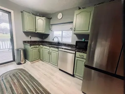 a kitchen with green cabinets and a stainless steel refrigerator at Retreat on Lake Milton in Berlin Center