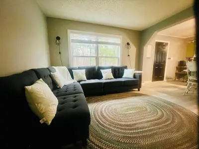 a living room with a blue couch and a rug at Retreat on Lake Milton in Berlin Center
