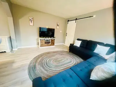 a living room with a blue couch and a rug at Retreat on Lake Milton in Berlin Center