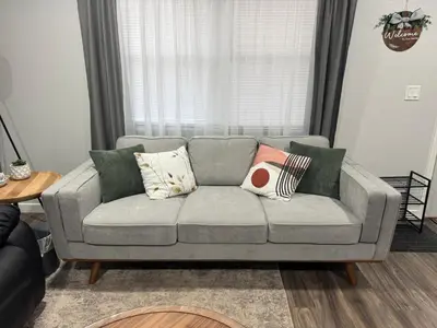a living room with a gray couch with pillows at Meadow View BNB in Lima