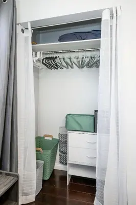 a bedroom with a bed with white curtains and drawers at Meadow View BNB in Lima