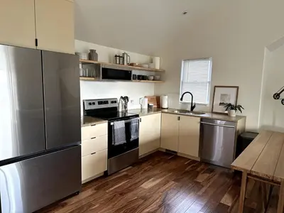 a kitchen with stainless steel appliances and wooden floors at Scandanavian Cottage with a View in Canonsburg