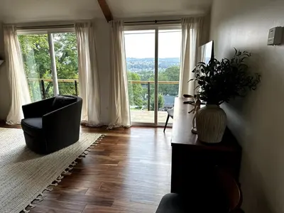 a living room with a chair and a large window at Scandanavian Cottage with a View in Canonsburg