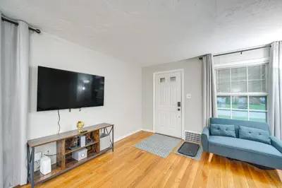 a living room with a blue couch and a flat screen tv at 2 Mi to Lake Erie Home with Yard in Euclid! in Euclid