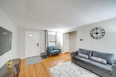 a living room with a couch and a clock on the wall at 2 Mi to Lake Erie Home with Yard in Euclid! in Euclid