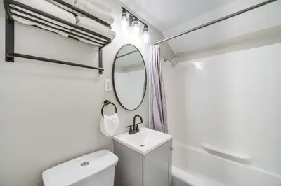 a white bathroom with a sink and a mirror at 2 Mi to Lake Erie Home with Yard in Euclid! in Euclid