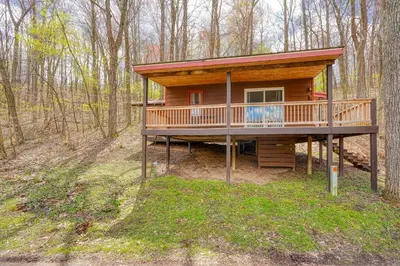 a log cabin with a deck in the woods at Wyandot Woods - Lake House in Laurelville