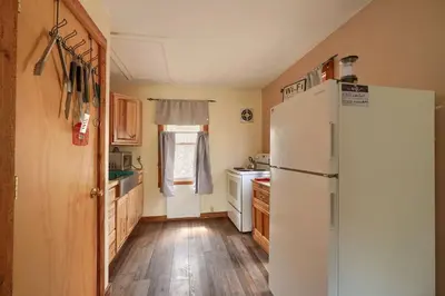 a kitchen with a white refrigerator and wooden floors at Wyandot Woods - Lake House in Laurelville