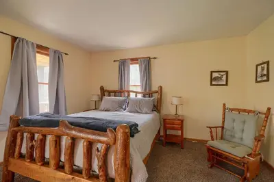 a bedroom with a wooden bed and a chair at Wyandot Woods - Lake House in Laurelville