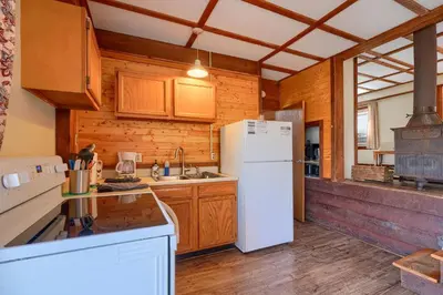 a kitchen with a white refrigerator and wooden cabinets at Wyandot Woods - Cedar House in Laurelville