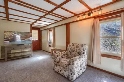 a living room with a chair and a television at Wyandot Woods - Cedar House in Laurelville