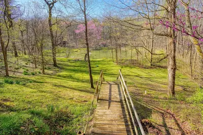 a wooden path in a field with trees and a bridge at Wyandot Woods - Hillside in Laurelville