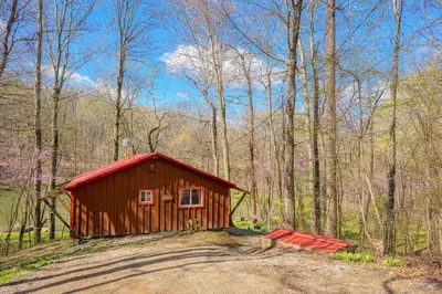 a small red cabin in the middle of a forest at Wyandot Woods - Squirrels Nest in Laurelville