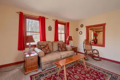a living room with a couch and red curtains at Wyandot Woods - Firefly in Laurelville