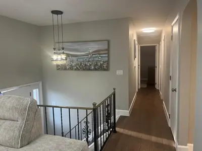 a stairway with a chair and a painting on the wall at Liberty Twp Spacious 4 bedroom house in Middletown