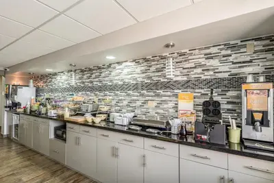 a kitchen with white cabinets and a brick wall at Quality Inn Grove City - Columbus South in Grove City
