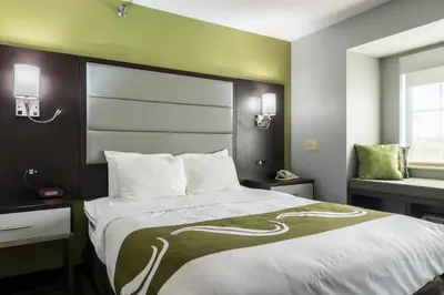 a bedroom with a large bed and a chair at Quality Inn Grove City - Columbus South in Grove City